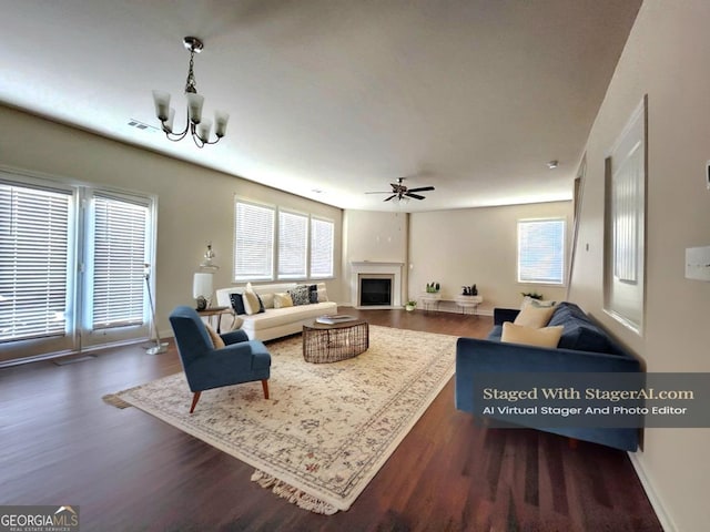 living room featuring ceiling fan with notable chandelier, dark wood-type flooring, and a wealth of natural light