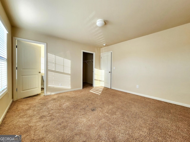 unfurnished bedroom with carpet flooring, a spacious closet, and a closet