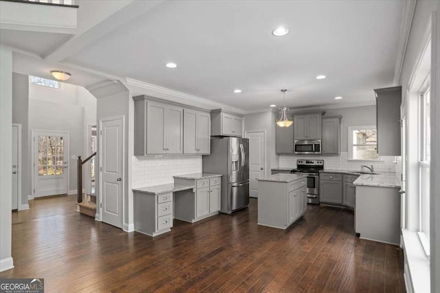 kitchen featuring appliances with stainless steel finishes, a center island, gray cabinets, and pendant lighting