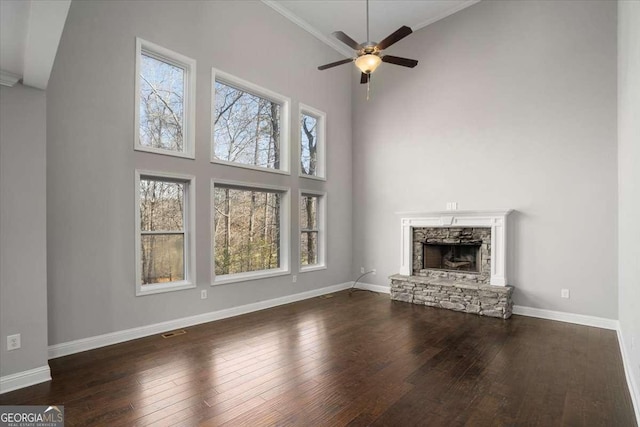 unfurnished living room with a high ceiling, crown molding, ceiling fan, dark hardwood / wood-style floors, and a fireplace