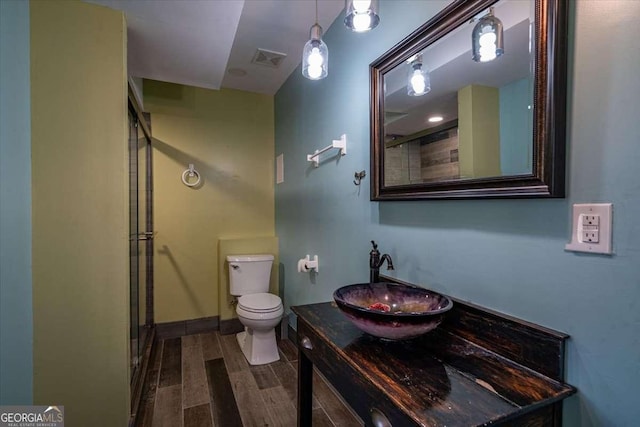 bathroom with a shower with door, vanity, and toilet