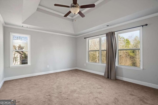 empty room featuring ceiling fan, light colored carpet, crown molding, and a tray ceiling