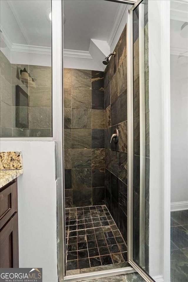 bathroom with a tile shower, vanity, and crown molding