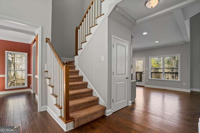 staircase featuring hardwood / wood-style floors, ornamental molding, and beam ceiling