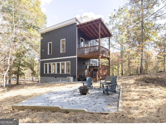 rear view of house with an outdoor fire pit and a wooden deck