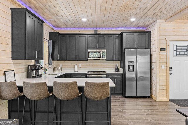 kitchen with a breakfast bar, wooden ceiling, sink, light wood-type flooring, and stainless steel appliances