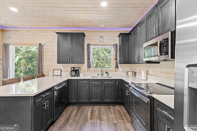 kitchen featuring sink, wooden ceiling, dark hardwood / wood-style floors, kitchen peninsula, and appliances with stainless steel finishes