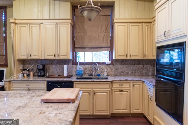 kitchen featuring cream cabinets, light stone counters, black appliances, and sink