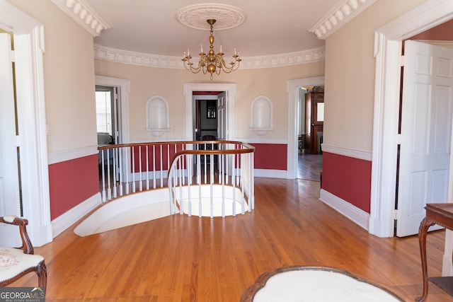 corridor featuring hardwood / wood-style floors, an inviting chandelier, and ornamental molding