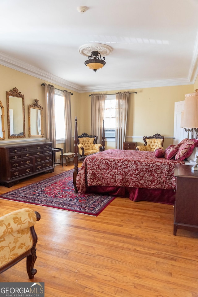 bedroom featuring multiple windows, crown molding, and light hardwood / wood-style floors