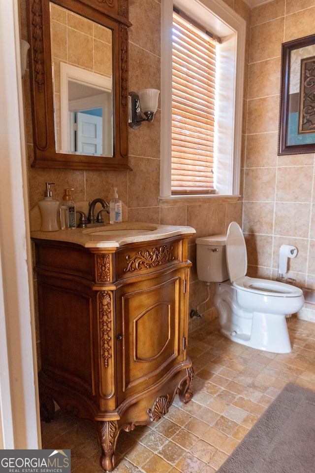 bathroom featuring vanity, tile walls, and toilet