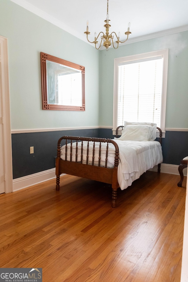 bedroom featuring hardwood / wood-style floors, crown molding, and a chandelier