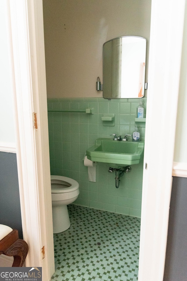 bathroom featuring sink, tile walls, and toilet