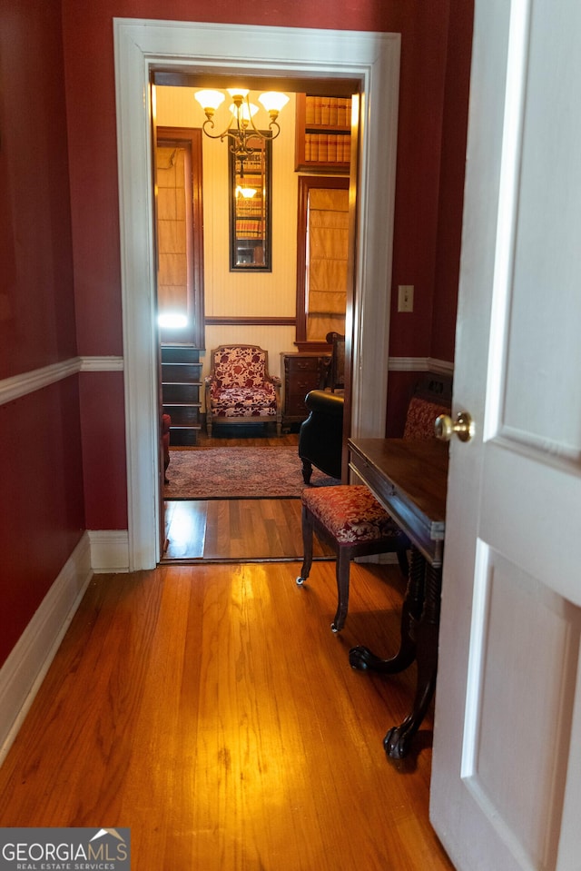 hall with hardwood / wood-style floors and an inviting chandelier