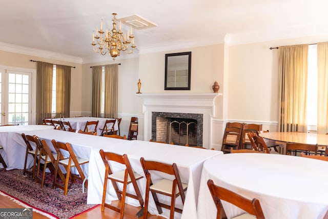 dining area with a chandelier, a high end fireplace, wood-type flooring, and ornamental molding