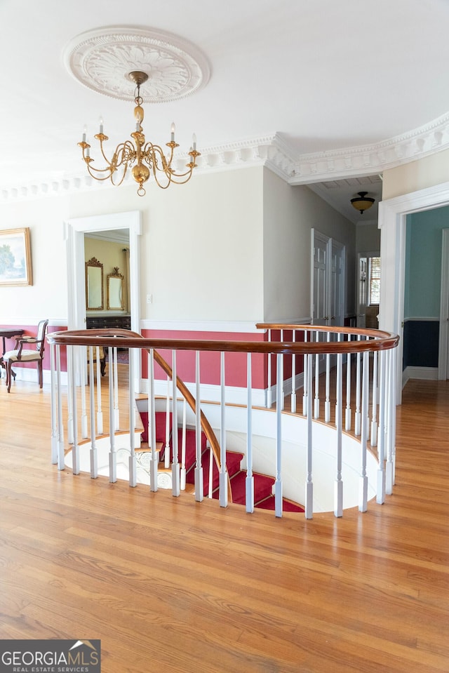 stairway with hardwood / wood-style flooring and a notable chandelier