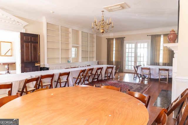 dining area featuring crown molding, a chandelier, and hardwood / wood-style flooring