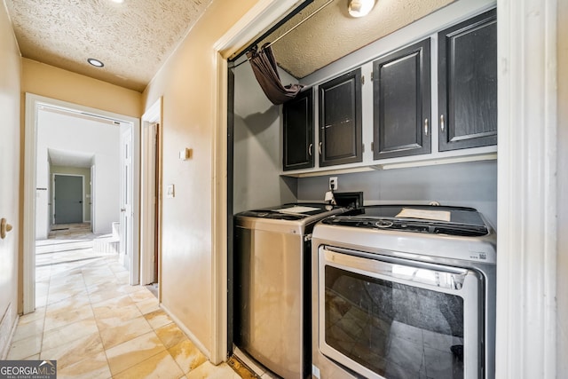 clothes washing area with cabinets, separate washer and dryer, and a textured ceiling