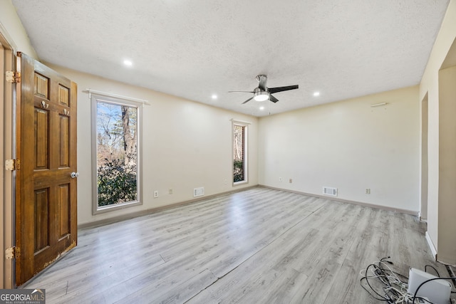 spare room with ceiling fan, a textured ceiling, and light wood-type flooring