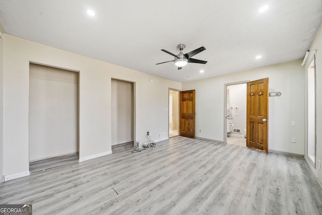 unfurnished bedroom with two closets, light hardwood / wood-style flooring, ceiling fan, and ensuite bathroom