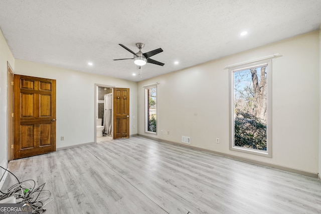 unfurnished bedroom with multiple windows, a textured ceiling, and light hardwood / wood-style flooring