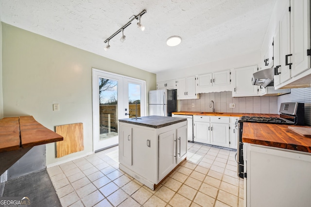 kitchen with wooden counters, white cabinetry, stainless steel appliances, extractor fan, and a kitchen island