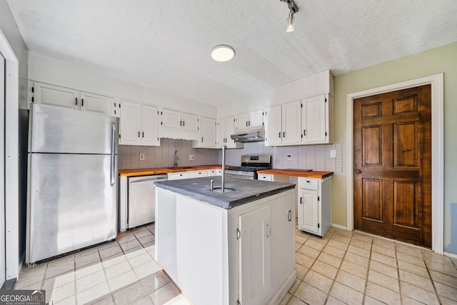 kitchen with wooden counters, a center island, white cabinets, and appliances with stainless steel finishes