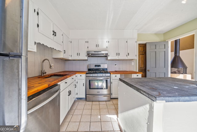 kitchen featuring appliances with stainless steel finishes, sink, butcher block countertops, and white cabinets