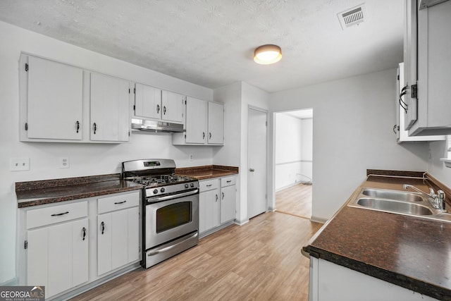 kitchen with white cabinetry, gas stove, a textured ceiling, light hardwood / wood-style flooring, and sink