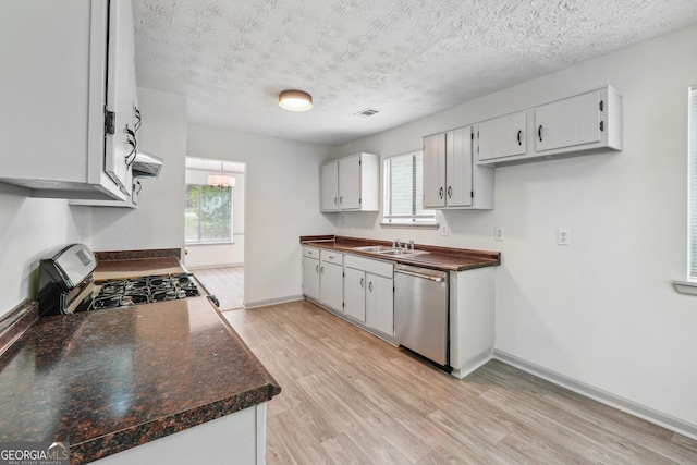 kitchen featuring light hardwood / wood-style floors, sink, appliances with stainless steel finishes, a textured ceiling, and white cabinets