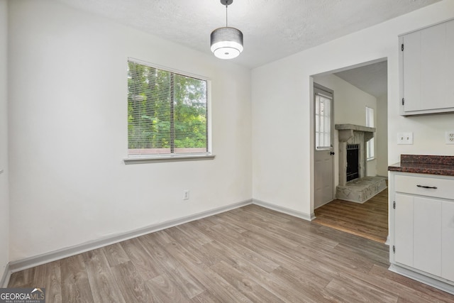 unfurnished dining area with a textured ceiling and light hardwood / wood-style flooring