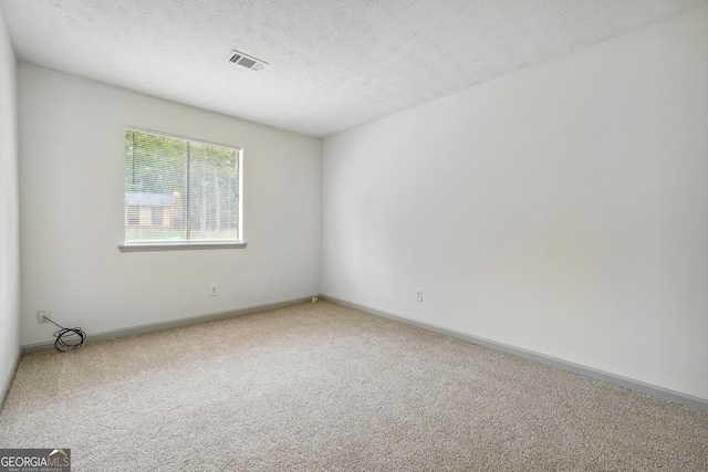 carpeted empty room featuring a textured ceiling