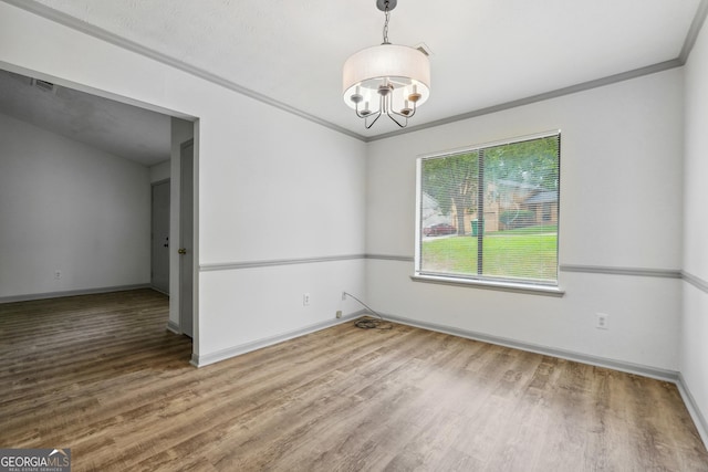 unfurnished room featuring crown molding, a chandelier, and hardwood / wood-style floors