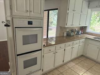 kitchen featuring double oven, sink, white cabinets, and light tile patterned floors