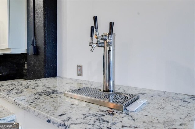 details with white cabinetry, light stone counters, and sink