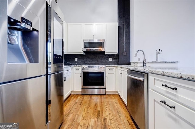 kitchen featuring light stone counters, sink, white cabinets, and stainless steel appliances