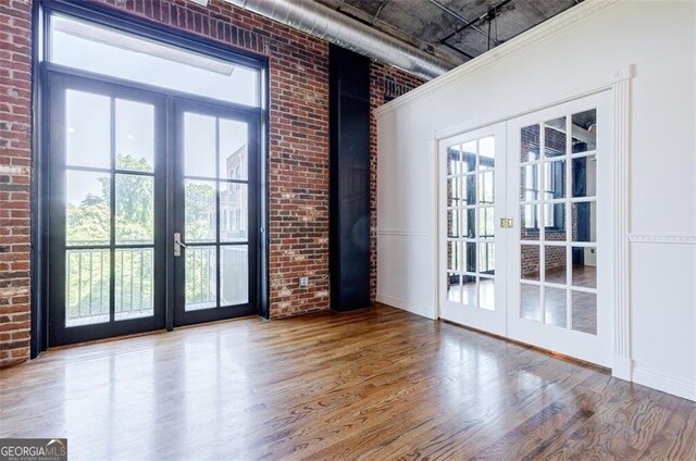 doorway to outside featuring hardwood / wood-style floors, french doors, and brick wall