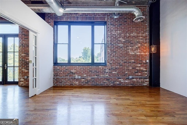 spare room with french doors, brick wall, and hardwood / wood-style flooring