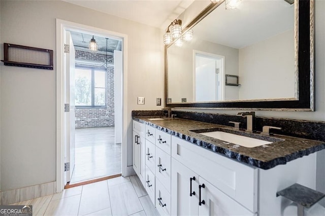 bathroom featuring vanity, tile patterned floors, and brick wall