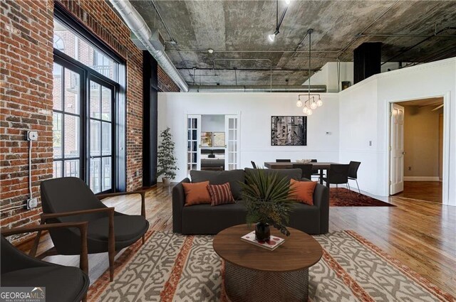 unfurnished room featuring hardwood / wood-style flooring, brick wall, a high ceiling, and french doors