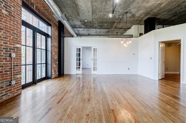 unfurnished room with dark hardwood / wood-style flooring, brick wall, and french doors