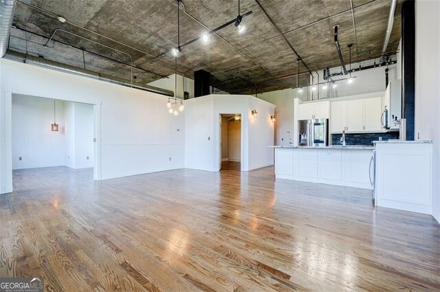 unfurnished living room featuring light hardwood / wood-style floors and a towering ceiling