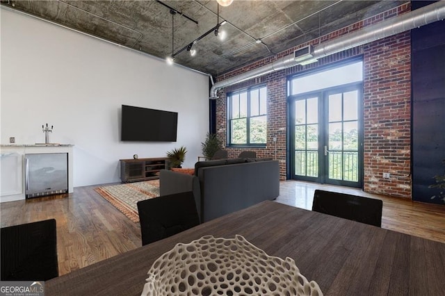 dining space featuring wood-type flooring, brick wall, and french doors