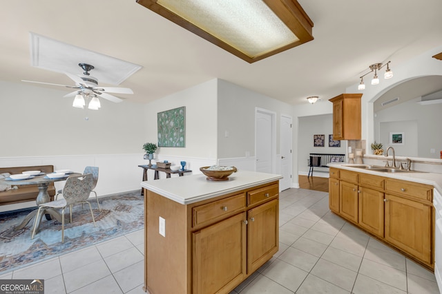 kitchen featuring light tile patterned floors, a kitchen island, ceiling fan, and sink