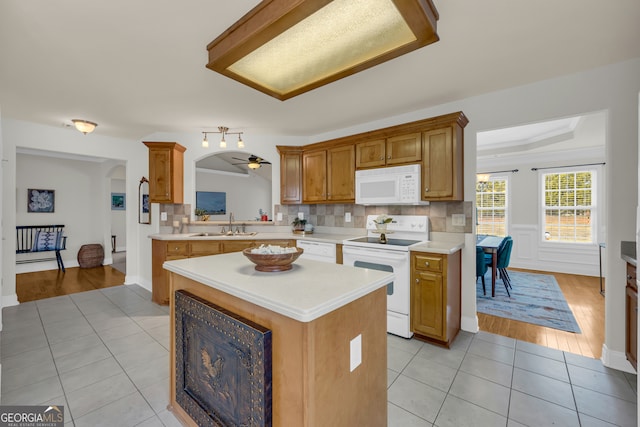 kitchen featuring a center island, white appliances, sink, ceiling fan, and light tile patterned floors