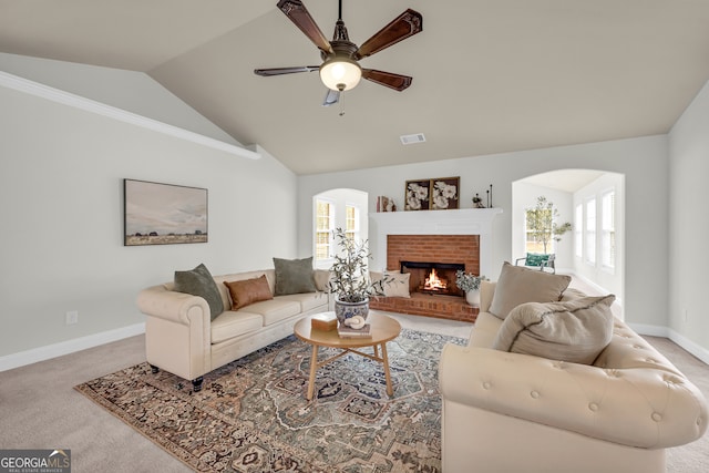 carpeted living room featuring a wealth of natural light, ceiling fan, vaulted ceiling, and a brick fireplace