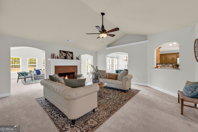 living room with light carpet, vaulted ceiling, a brick fireplace, and ceiling fan