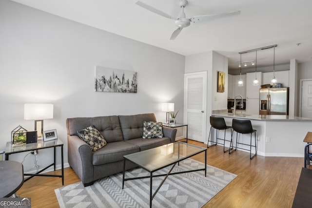 living room with ceiling fan, light wood-type flooring, and sink