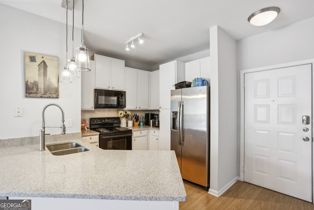 kitchen with sink, hanging light fixtures, kitchen peninsula, white cabinets, and black appliances