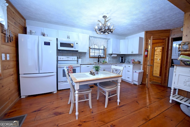 kitchen with white cabinetry, decorative light fixtures, and white appliances